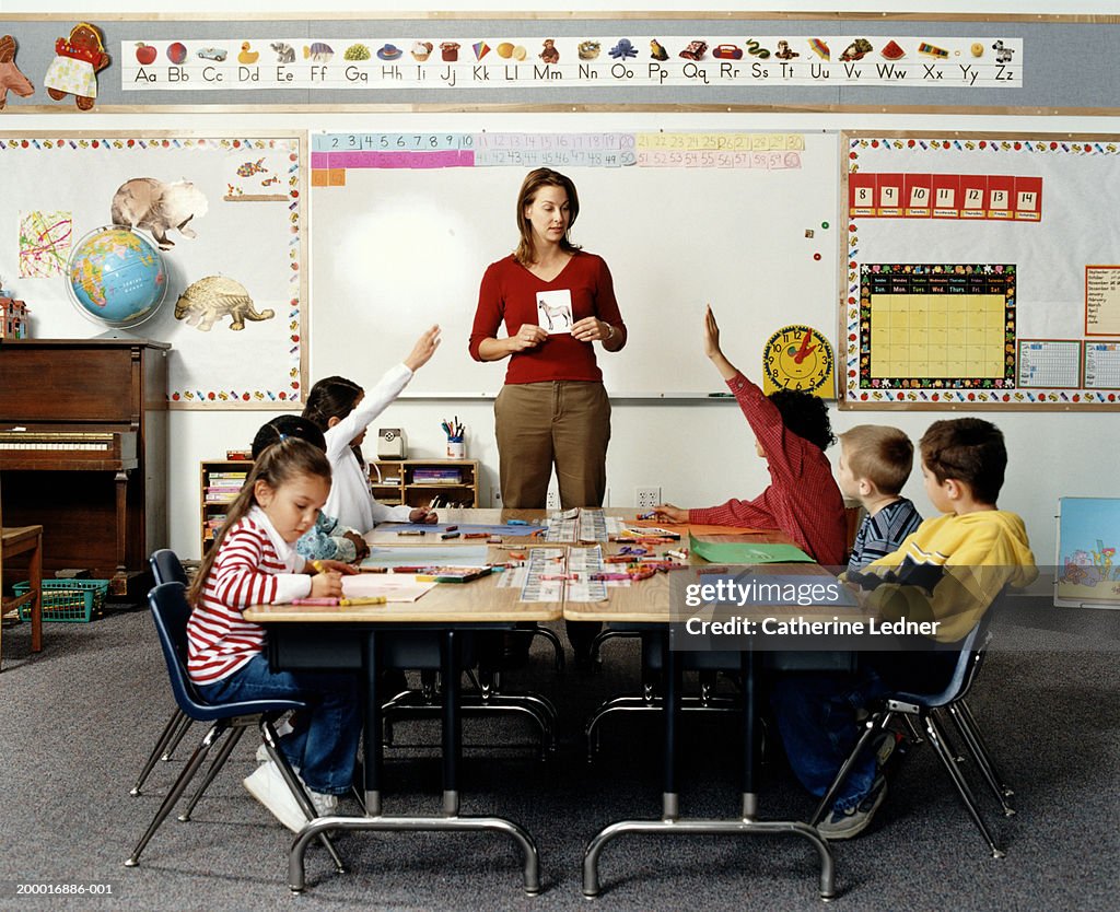 Teacher holding flashcard in front of children (5-7)