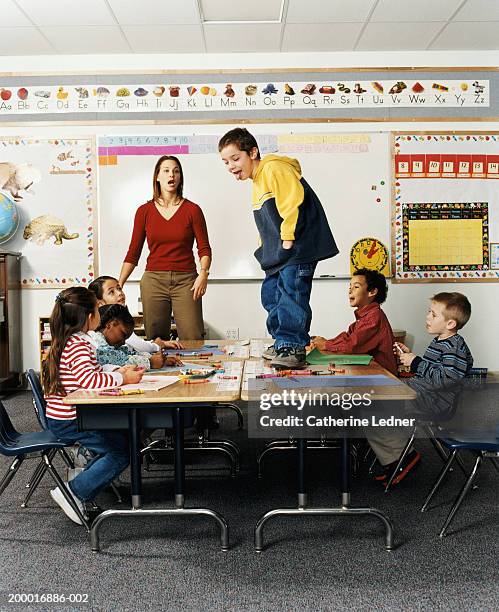 boy (5-7) standing on desk in front of class - student uprising stock pictures, royalty-free photos & images