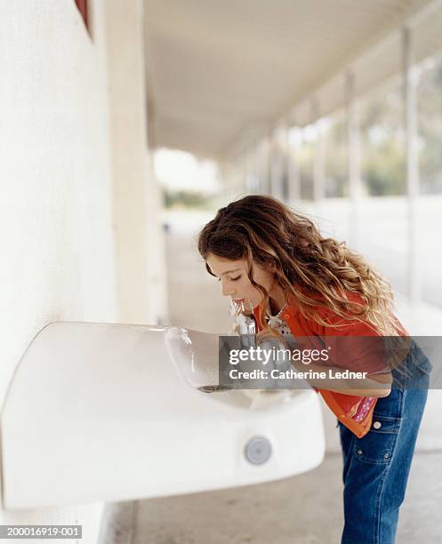 girl (5-7) drinking from water fountain in school hallway - drinking fountain stock pictures, royalty-free photos & images