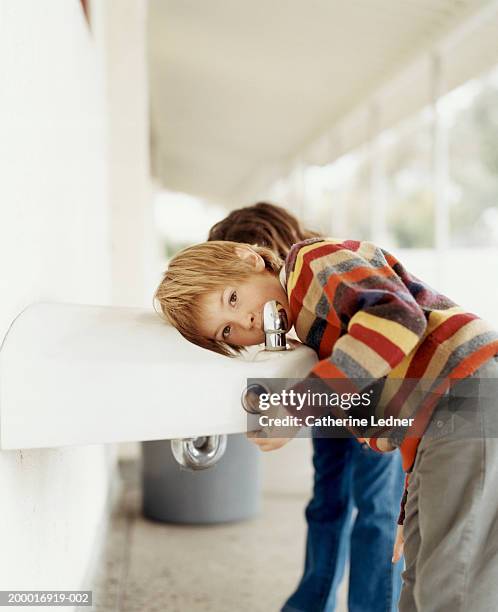 children (5-7) drinking from water fountain in school hallway - drinking fountain stock pictures, royalty-free photos & images