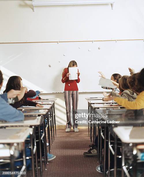 students throwing paper balls at girl (14-16) reading paper - bully school stock pictures, royalty-free photos & images