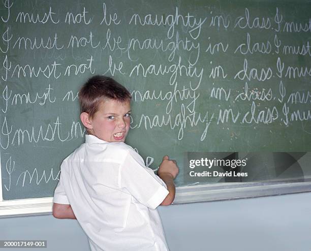 school boy (7-9) writing lines on blackboard, portrait - stand grammar school stock pictures, royalty-free photos & images