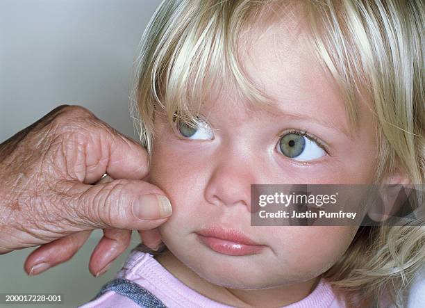 elderley woman pinching cheek of female toddler, close-up - pinching stock pictures, royalty-free photos & images