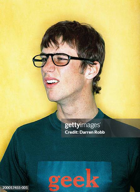 young man wearing glasses and 'geek' t-shirt, close-up - geek stock-fotos und bilder