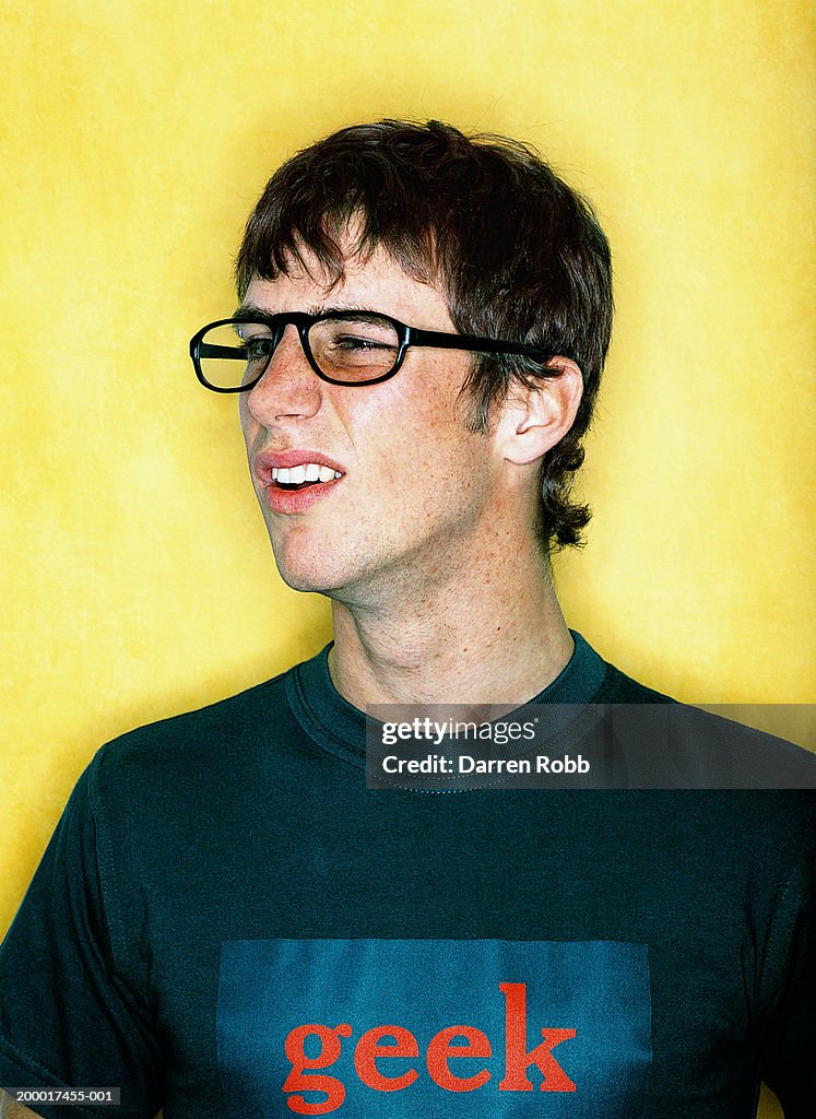 Young man wearing glasses and 'geek' T-shirt, close-up