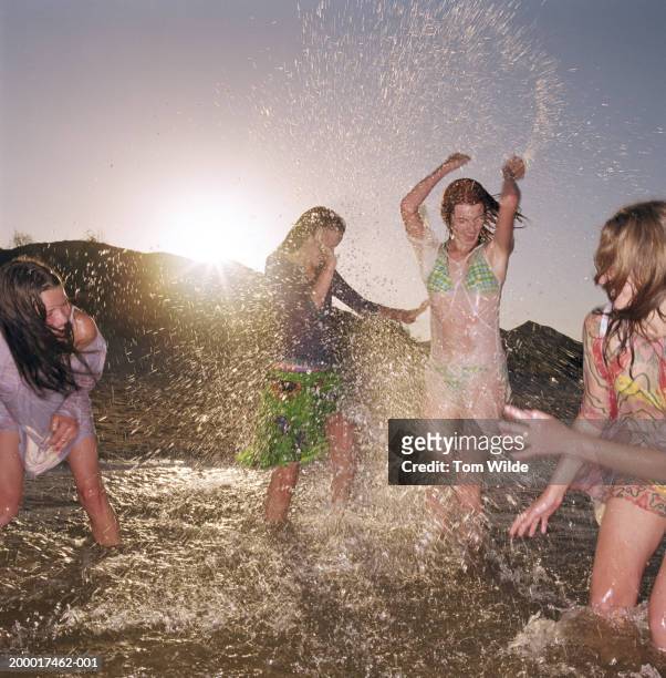 four teenage girls (14-17) splashing in water - alleen tienermeisjes stockfoto's en -beelden