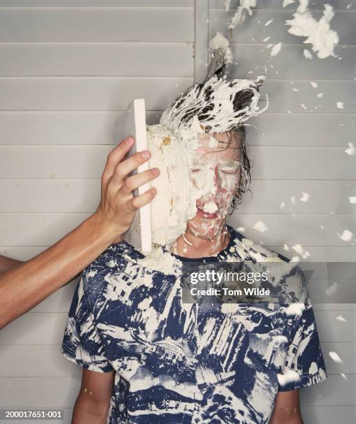 young man covered in cream, cake squashed into face, close-up - flip over stockfoto's en -beelden