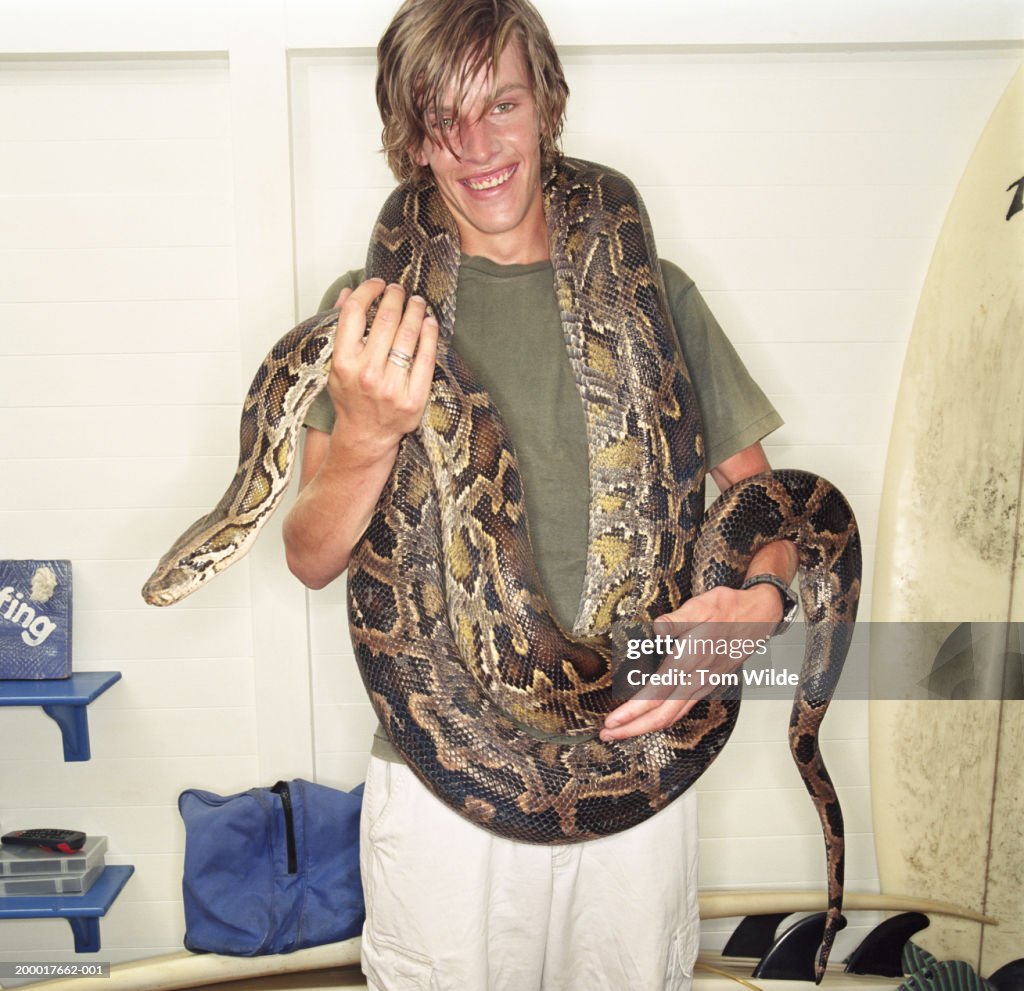 Young man with burmese python (Python molurus bivittatus) on shoulders
