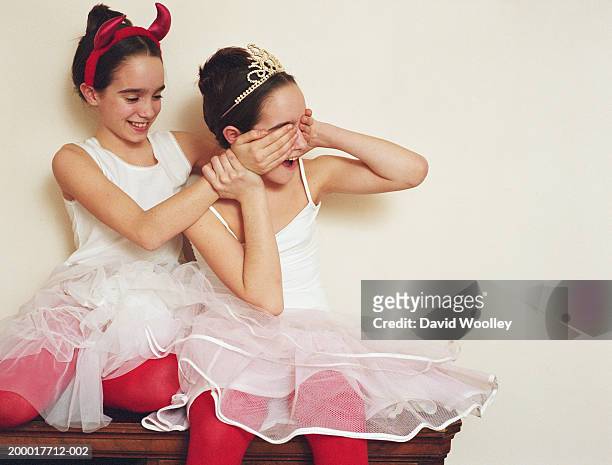 twin sisters (11-13) in tutus, one covering other's eyes - evil twin stock pictures, royalty-free photos & images