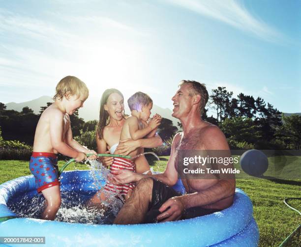 parents and sons (2-4) playing in paddling pool - two kids playing with hose stock pictures, royalty-free photos & images