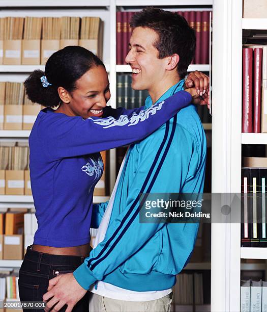 young couple embracing in library, laughing - embarrassed girlfriend stock pictures, royalty-free photos & images