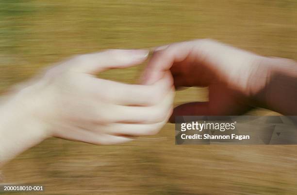 young couple holding hands, close-up (blurred motion) - holding hands close up stock-fotos und bilder