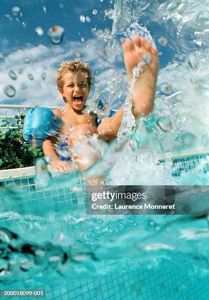 boy (4-6) at edge of swimming pool splashing water - waters edge imagens e fotografias de stock