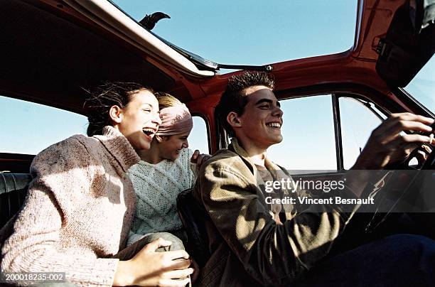 three teenagers (14-18) in car with open sunroof - car journey stockfoto's en -beelden