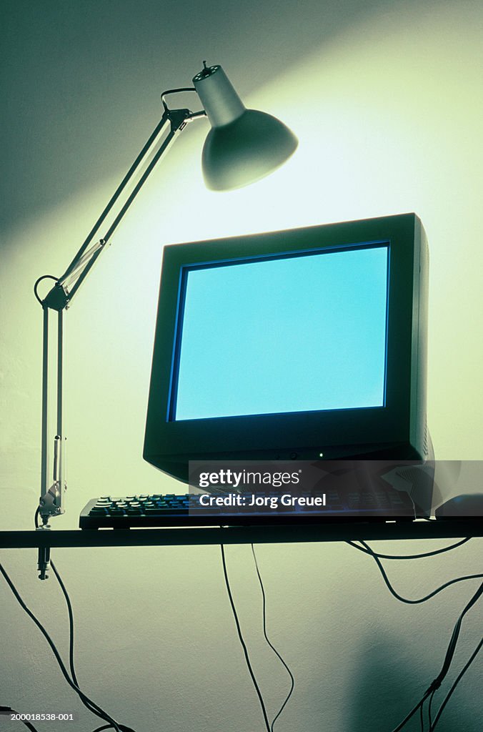 Desk lamp shining over computer