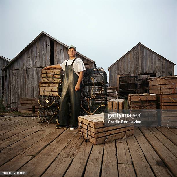 man standing near lobster crates on dock - fisherman stock-fotos und bilder