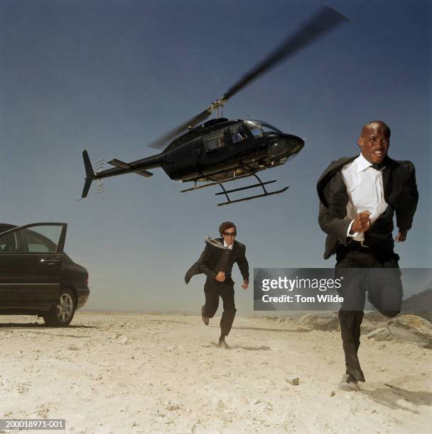 two men running from helicopter in desert - verfolgen stock-fotos und bilder