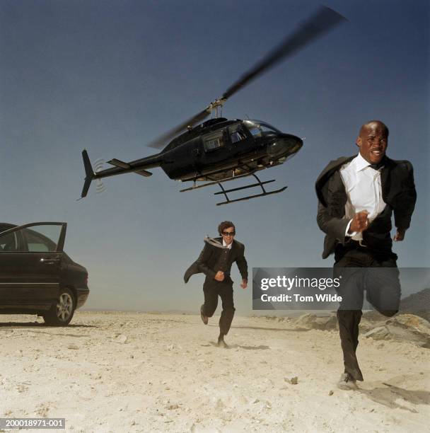 two men running from helicopter in desert - fuga fotografías e imágenes de stock