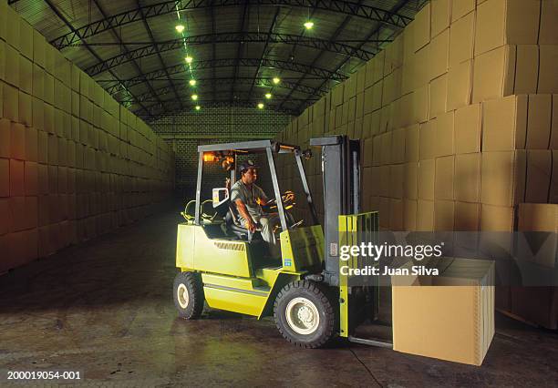 man driving forklift with boxes in warehouse - forklift truck stock pictures, royalty-free photos & images