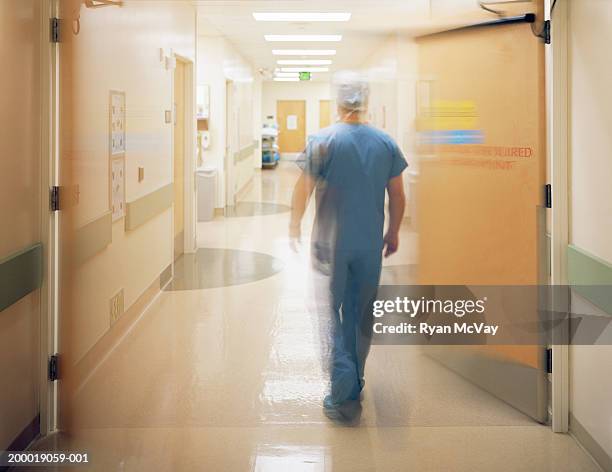 male surgeon walking down corridor, rear view (blurred motion) - hospital corridor stock pictures, royalty-free photos & images