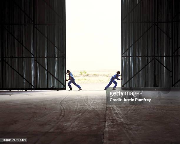 two men opening warehouse doors - ドア 開く ストックフォトと画像