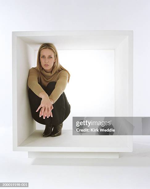 young woman crouching inside white box - trapped stock pictures, royalty-free photos & images