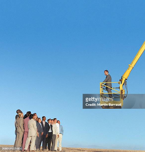 businessman addressing group of people from cherry picker - cherry picker photos et images de collection