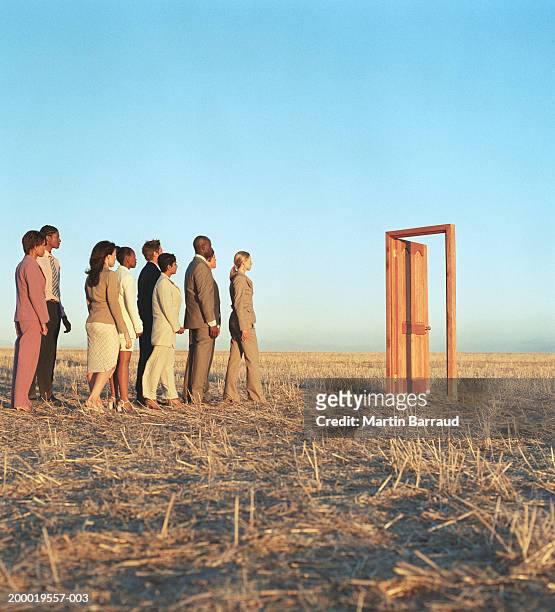 queue of people heading towards open door in field - businessman in black suit photos et images de collection