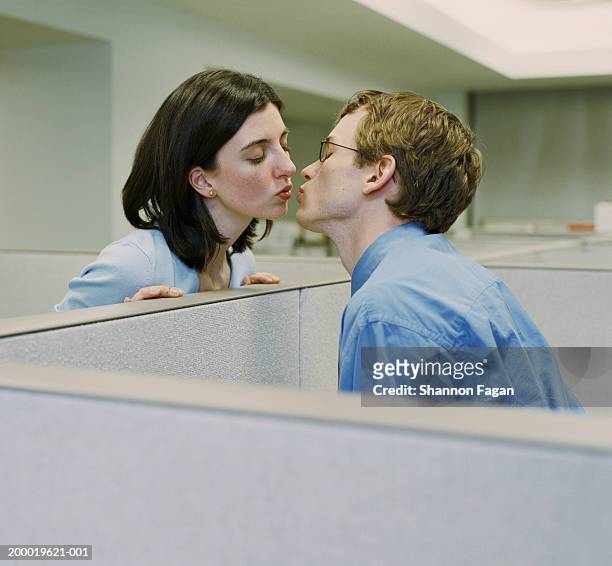 man and woman in seperate cubicles, kissing - kantoorromance stockfoto's en -beelden