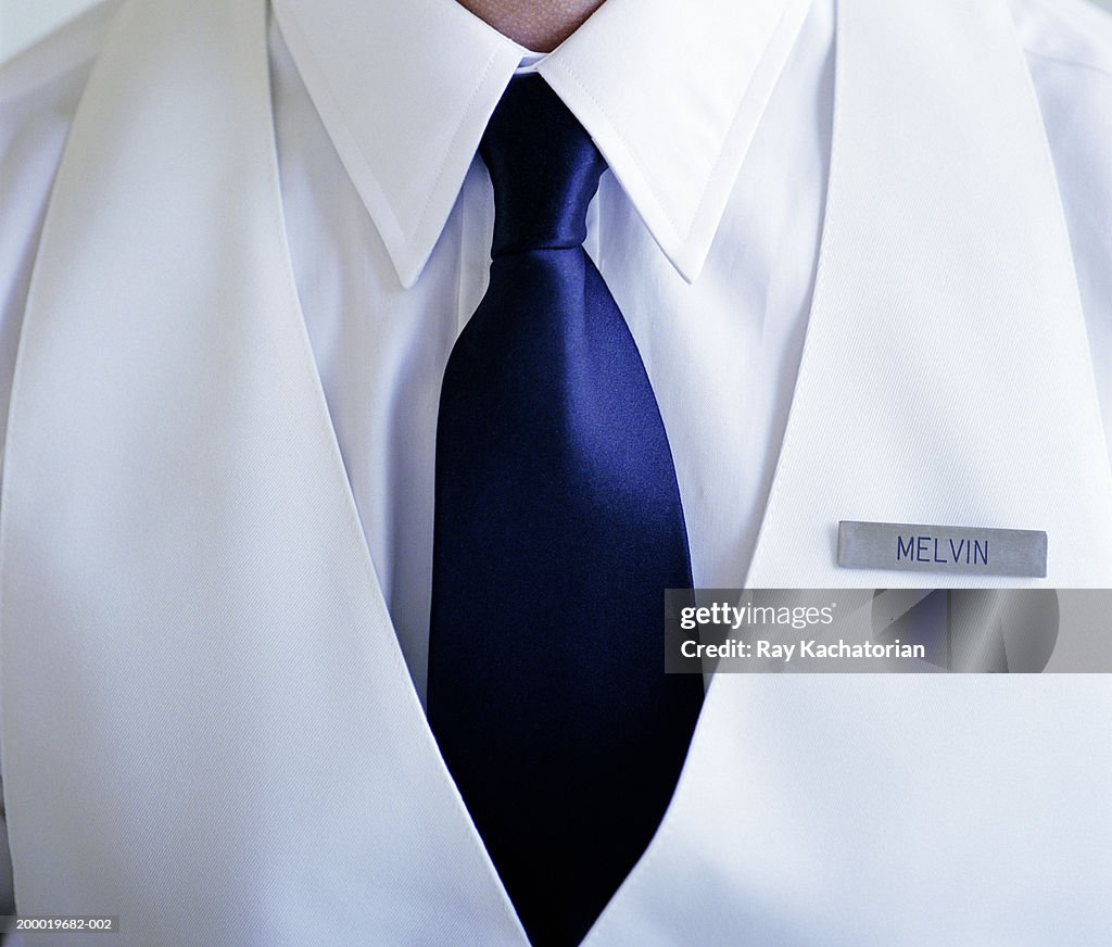 Man wearing white shirt and blue tie with name tag