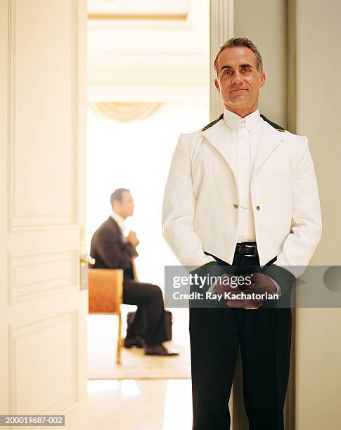 personal valet standing outside room, businessman in background - butler stock pictures, royalty-free photos & images