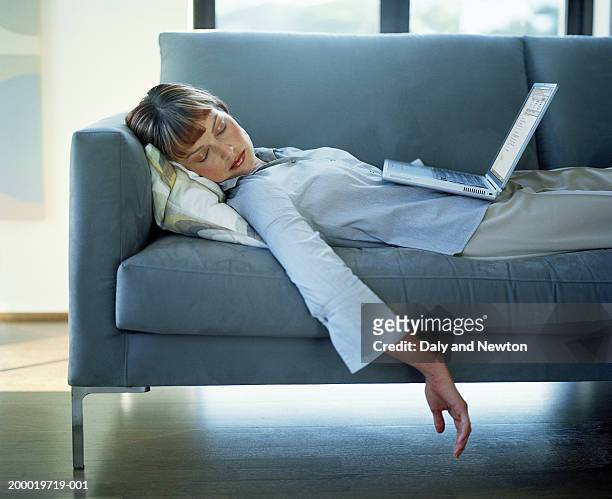 young woman sleeping on sofa, laptop resting on stomach - exaustão imagens e fotografias de stock