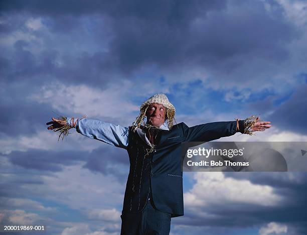 man dressed as scarecrow standing under cloudy sky - scarecrow agricultural equipment stock-fotos und bilder