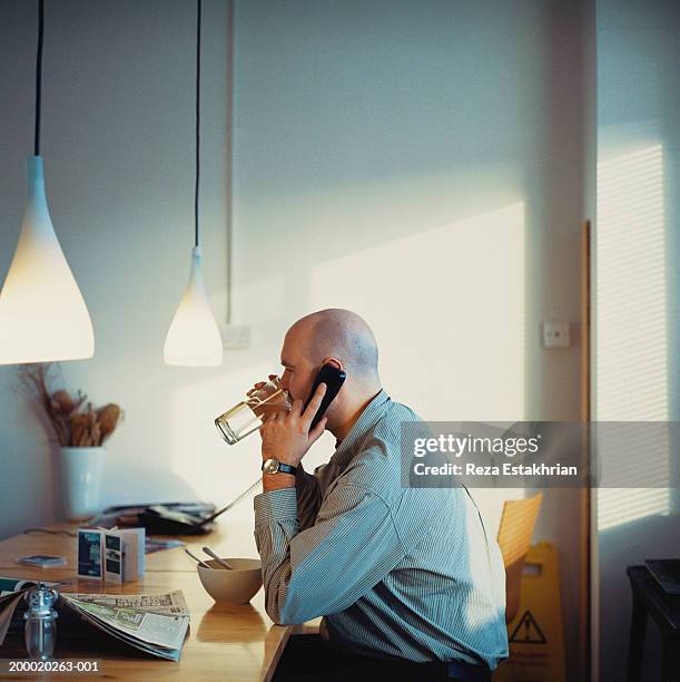 businessman at counter drinking water whilst using telephone - telefone fixo imagens e fotografias de stock