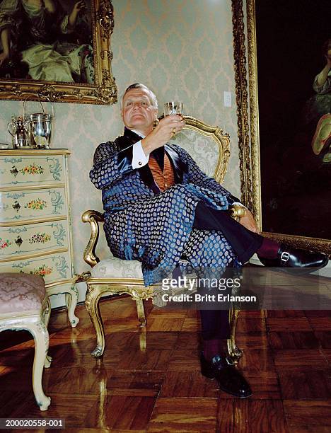 mature man wearing smoking jacket raising glass, portrait - upper class stock pictures, royalty-free photos & images