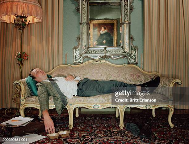 man sleeping on sofa, paperwork on floor - antique sofa styles foto e immagini stock