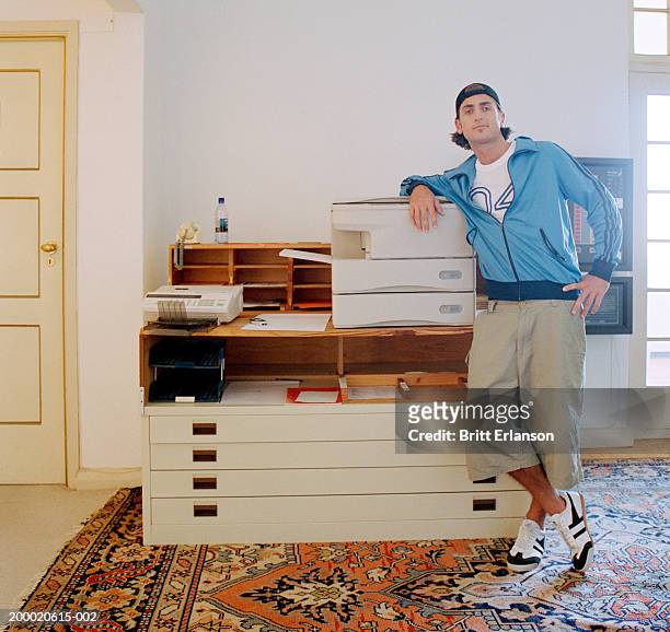 young man leaning on photocopier in office, portrait - de atrás hacia adelante fotografías e imágenes de stock