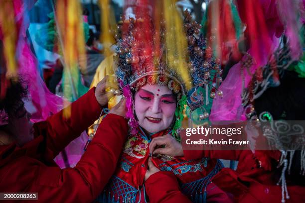 Chinese folk artist is helped with her costume while sitting in a sedan chair as she and others prepare to perform for the Chinese Lunar New Year at...