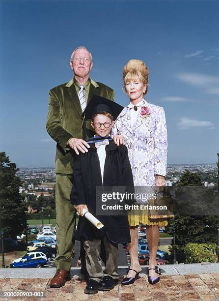 boy (7-9) wearing graduation cap and gown with parents, portrait - kids certificate stock pictures, royalty-free photos & images