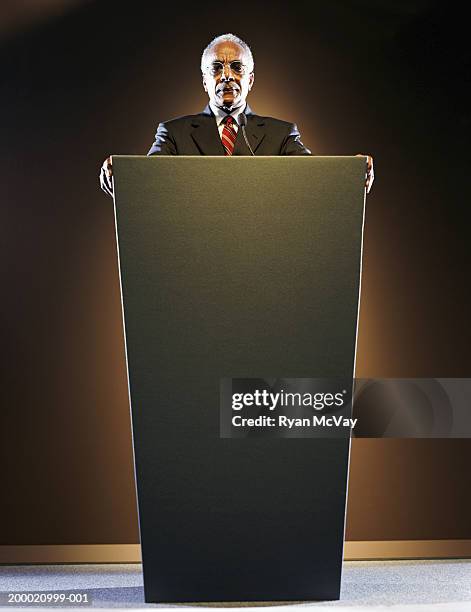 elderly man standing at podium - lectern stock-fotos und bilder