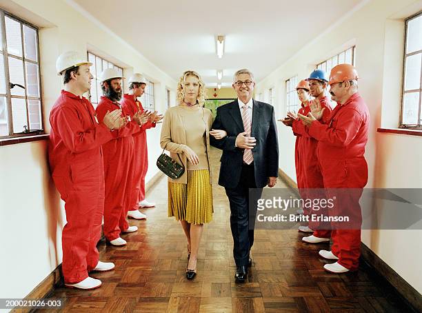 mature man and young woman walking between workmen clapping, portrait - girls jumpsuit stock pictures, royalty-free photos & images