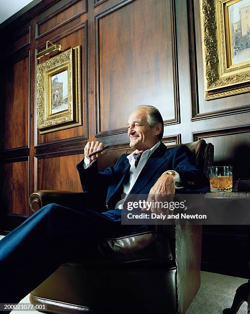 mature man sitting in leather chair, smoking cigar - crevettes stock pictures, royalty-free photos & images