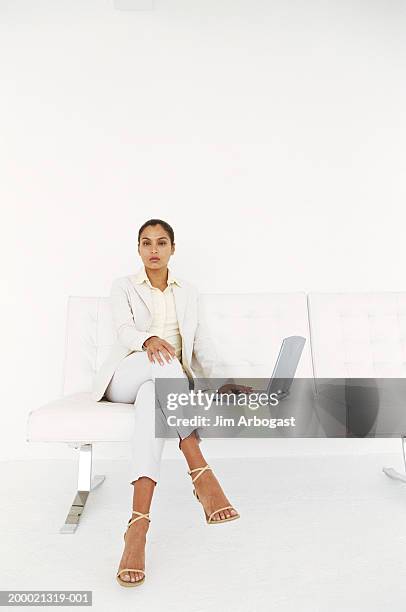 businesswoman sitting on white sofa with laptop computer - businesswoman couch fotografías e imágenes de stock