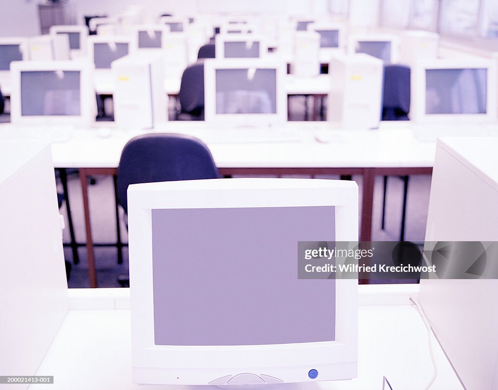Rows of computer terminals, focus on monitor in foreground