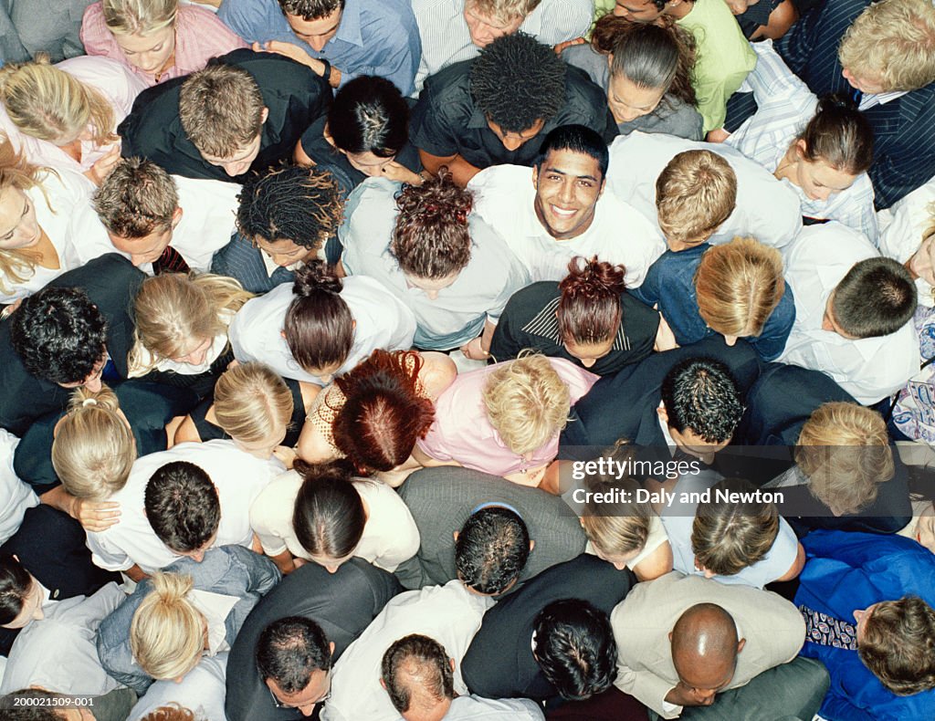 Young man in crowd of people looking up, portrait, overhead view