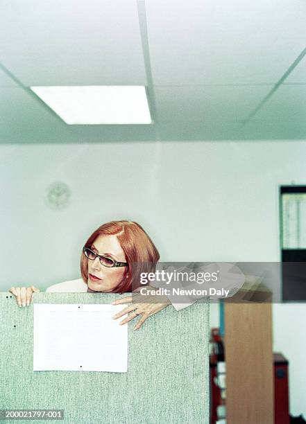 mature businesswoman looking over partition - entrometido fotografías e imágenes de stock