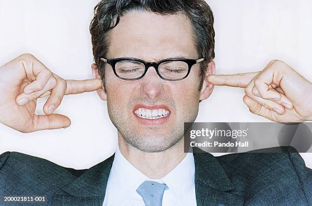 businessman, fingers in ears, eyes closed, close-up - hear no evil stock pictures, royalty-free photos & images