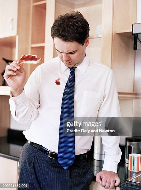 businessman eating toast, looking at jam spot on shirt - stained stock pictures, royalty-free photos & images