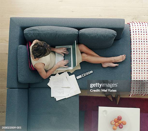 woman on sofa using laptop computer, overhead view - coffee table from above stock-fotos und bilder