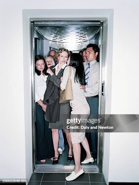 young woman squeezing into crowded lift - elevator fotografías e imágenes de stock